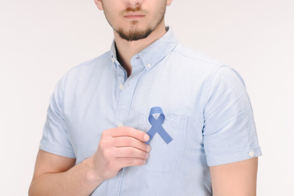 partial view of man with blue awareness ribbon isolated on white, colon cancer concept