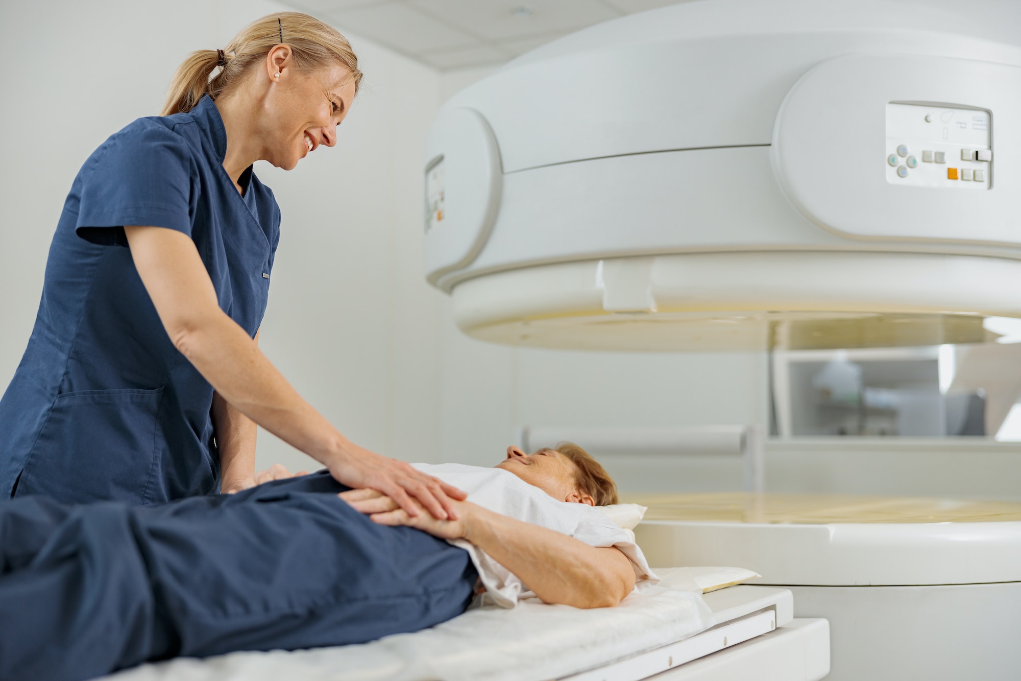 Radiologist controls MRI or CT or PET Scan with female patient undergoing procedure